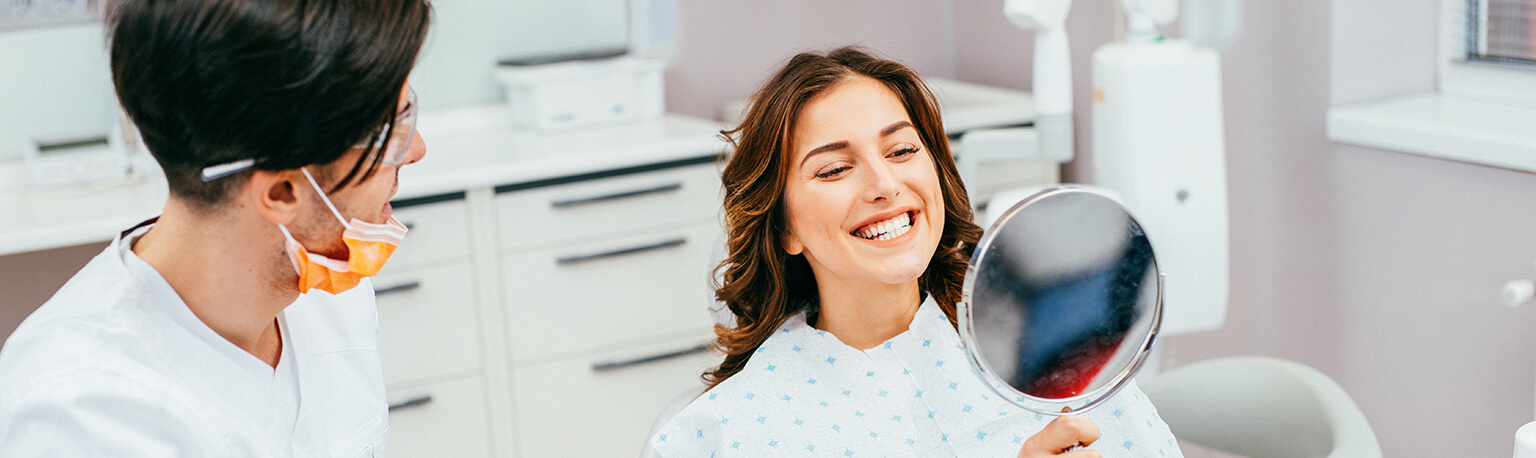 woman looking at her smile in a mirror